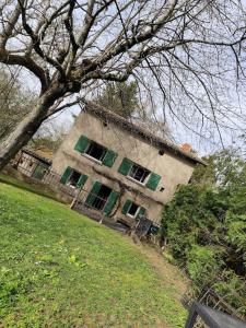 una vecchia casa con finestre con persiane verdi in un campo di la maison aux volets vert a Chaméane