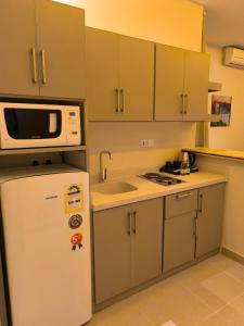 リヤドにあるTaleen Serviced Apartments AlQudsの白い冷蔵庫と電子レンジのあるキッチン