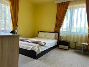 a bedroom with a bed in a room with windows at Complex MONACO HOTEL & CASINO in Svilengrad