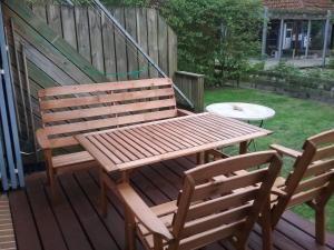 a wooden bench and two chairs on a deck at Ferienwohnung im Kapitänsgarten in Prerow in Prerow