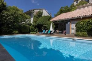 a swimming pool in front of a house at The Originals City, Hôtel de Bordeaux, Bergerac centre in Bergerac