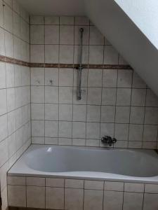 a bath tub with a shower in a tiled bathroom at Neu renovierte Wohnung in Alter Schule in Hattgenstein +27 photos