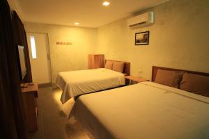 ein Hotelzimmer mit zwei Betten und einem Fernseher in der Unterkunft Bale Karang Cottages in Batukaras + 32 Fotos