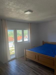a bedroom with a blue bed and a window at Vidovdanska house in Šipovo