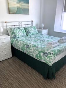 a bedroom with a bed with a green and white comforter at Donnington Guesthouse in Truro +6 photos