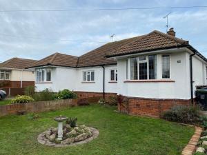 a white house with a brick fence and a yard at Eclectic Bungalow Parking Nr Beach in Kent
