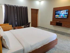 a bedroom with a bed and a tv on a wall at Shivanta Resort and Hotel in Deoghar