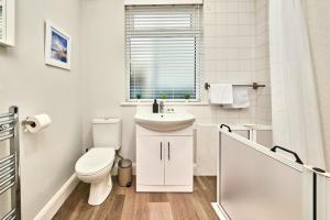 a white bathroom with a toilet and a sink at Princess Yellow 1 - Portrush by the Sea in Portrush +43 photos