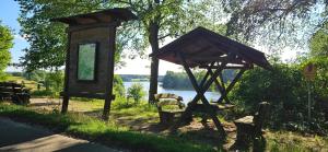 a small wooden structure with chairs and a tree at Mietwohnwagen inklusive Stellplatz & Strom - Dixi-WC in Carpin