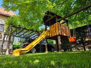 a playground with a yellow slide in a yard at Szilvás 10 in Szigliget
