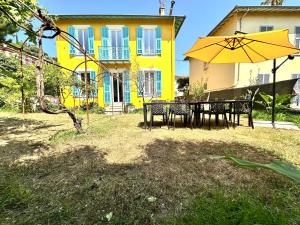 a yellow house with a table and an umbrella at Villa Lila in Nice