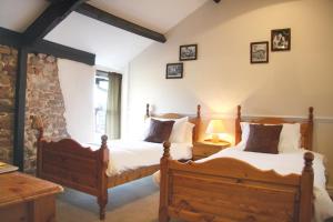 two beds in a bedroom with a stone wall at Boot & Shoe Inn in Greystoke