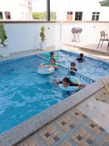 a group of children playing in a swimming pool at Hakeem Homestay in Pokok Sena