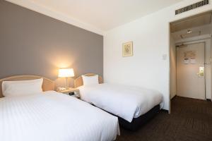 two beds in a hotel room with white sheets at Tottori Washington Hotel Plaza in Tottori