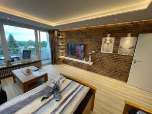 una camera da letto con un muro di mattoni, un letto e una TV di Haus Weitblick Emil a Flensburgo