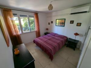 una camera con letto viola e finestra di F3 RDC jardin clôt et piscine privatifs, proche toutes activités ! ad Agde
