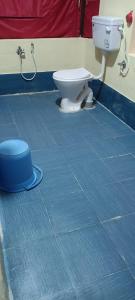 a bathroom with a toilet and a blue tiled floor at Bhitarkanika Eco Resort TENT in Righāgarh