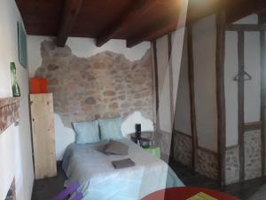 una camera da letto con un letto e un muro di pietra di Odyssée a Vallon-en-Sully