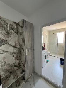bagno con parete in pietra e porta doccia di Suli Beach Apartments a Tale