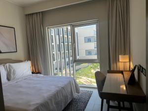 a hotel room with a bed and a desk and a window at Address Beach Marassi Residence in El Alamein +10 photos