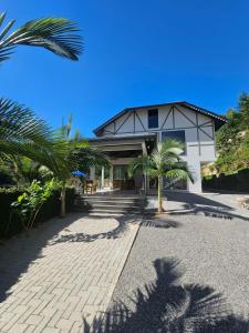 a building with palm trees in front of it at Pousada & Hospedagem Estação in Domingos Martins