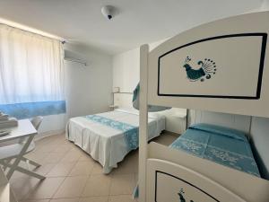 a room with a bed and a table and a desk at Garden Hotel Alghero in Fertilia