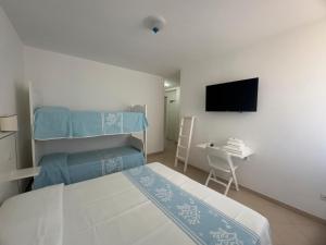 a bedroom with a bed and a desk and a tv at Garden Hotel Alghero in Fertilia
