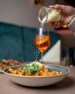 a person sprinkling sauce on a bowl of food at Hotel Restaurant Wolfsschlucht GmbH in Bad Münstereifel +80 photos