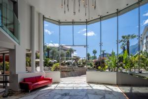 a room with a red couch in a building with large windows at Garda Suite Hotel - Tonelli Hotels in Riva del Garda +140 photos