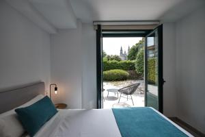 Un dormitorio con una cama y una puerta corrediza de vidrio. en Hotel Pombal Rooms, en Santiago de Compostela