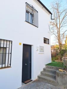a white house with a black door and stairs at Casa rural El Rincón de la Yedra in Setenil