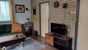 a living room with a couch and a flat screen tv at Vrijstaande bungalow bij het bos in het Vechtdal in Arriën