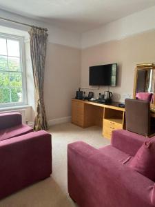 a living room with two purple couches and a tv at Royal Victoria Hotel Snowdonia in Llanberis