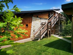 a building with wooden stairs next to a yard at Les Gîtes Vu d'Ici in La Chapelle-en-Vercors