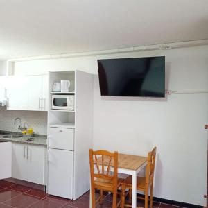 a kitchen with a table and a tv on a wall at APAR MARI 2c in Las Lagunas