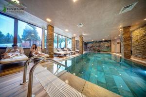 a house with a swimming pool with two people sitting at Aparthotel Forest Nook in Pamporovo