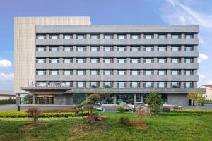 un grand bâtiment avec des voitures garées devant dans l'établissement Mehood Hotel, Changzhou Jintan Babaiban, à Jintan