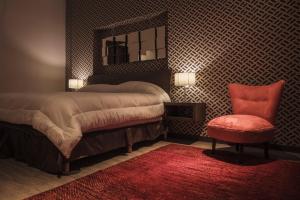 a bedroom with a bed with a mirror and a red chair at Hotel Platino Expo in Guadalajara