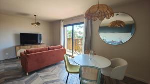 un soggiorno con un divano, un tavolo e uno specchio di L'appart Lila - Jacuzzi vue mer a Lacanau