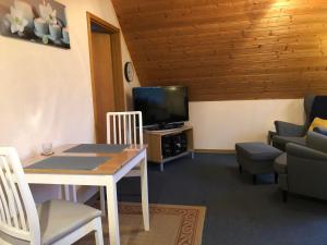 Una sala de estar con una mesa y un televisor. en Ferienwohnung Tammen, en Westoverledingen