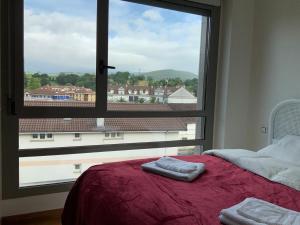 a bedroom with a large window and a bed with towels at Piso los Rosales in Sarón