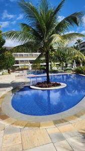 een palmboom in het midden van een zwembad bij Paraíso Malawí Flat Muro Alto in Porto De Galinhas