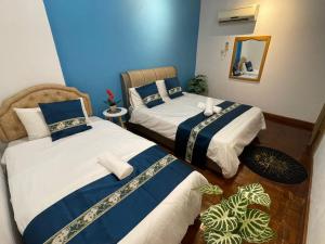 two beds in a room with blue walls at Riverbank 904 in Kuching