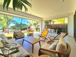 a living room with couches and chairs and a patio at Villa Beaux Souvenirs in Pointe d'Esny