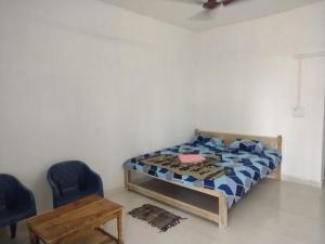 ein Schlafzimmer mit einem Bett und zwei blauen Stühlen in der Unterkunft Annapurna beach resort in Malvan + 22 Fotos