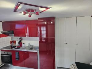 a red kitchen with white cabinets and a sink at Petit Duplex in Honfleur
