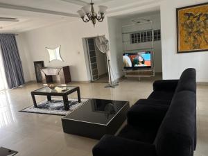 a living room with a couch and a table and a tv at Apartment Three Oranges SH 75 E Nza Street Independence Layout Enugu in Mama