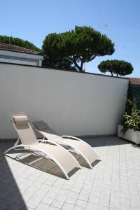 twee ligstoelen naast een witte muur bij Case VacanzeRò in Ravenna