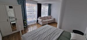 a bedroom with a bed and a chair and a window at Apartamente Dragasani in Drăgăşani