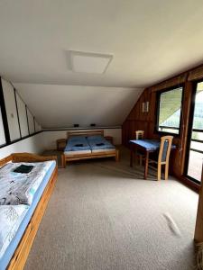 a bedroom with two beds and a table in it at Chata s výhledem do údolí Frymburk, Náhlov in Frymburk